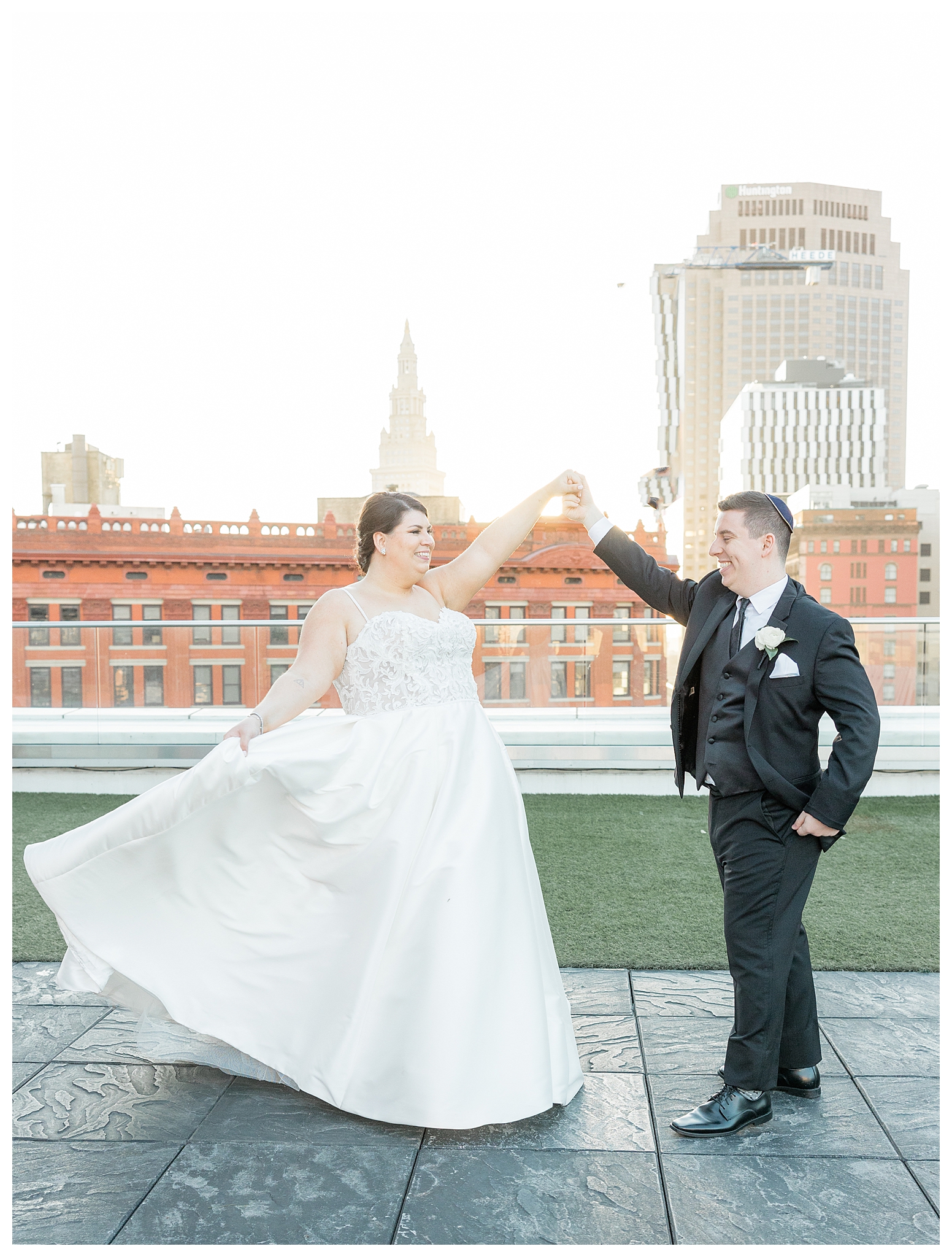 Bride spinning dress while holding groom's hand on a rooftop in Cleveland Ohio